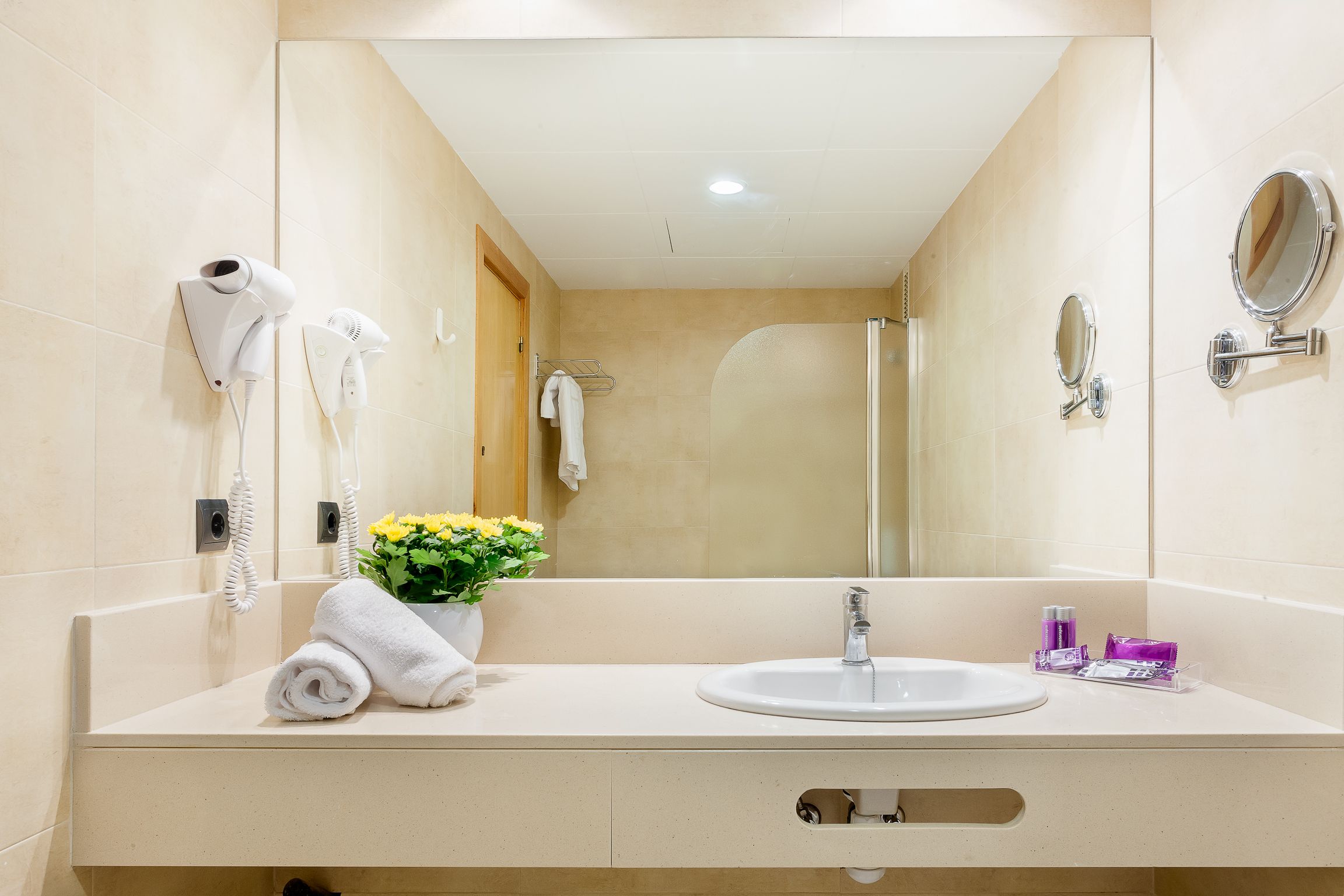 A bathroom with a sink, mirror, towel rack, and a shower.