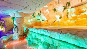A spa area with a rock wall, a hot tub, and a waterfall feature. - Beverly Park Hotel & Spa (Blanes)