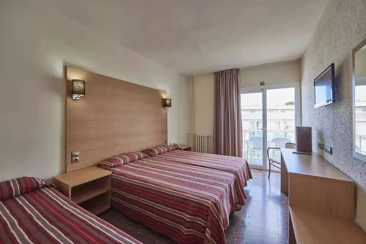 Une chambre d’hôtel avec deux lits, un bureau, une télévision et un balcon avec des rideaux.