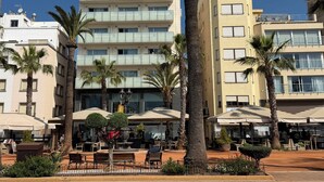 A hotel with multiple floors, outdoor seating, and palm trees.