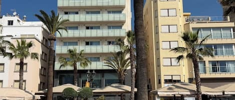 A hotel with multiple floors, outdoor seating, and palm trees.