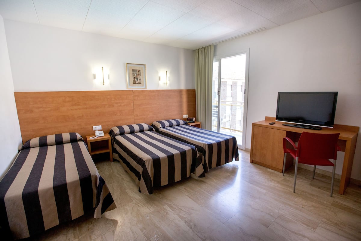 A hotel room with two single beds, a desk with a TV, and a chair.