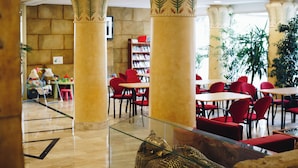 A lobby with a glass coffee table, red chairs, and a bookshelf. - Cleopatra Spa Hotel (Lloret de Mar)