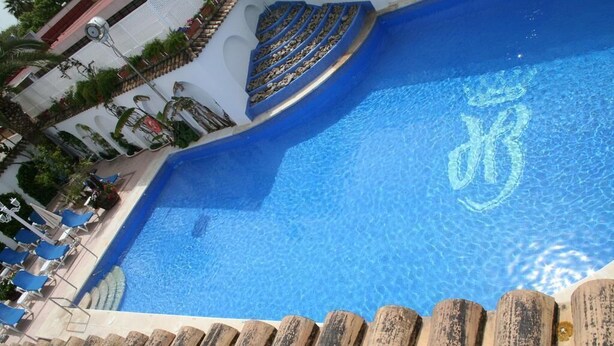 A swimming pool with a curved edge and a blue pattern on the water. - Brasilia (Chipiona)