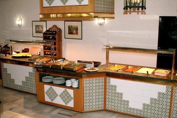 Un espace buffet avec différents postes de service pour les plats, un présentoir à bouteilles de vin et une vitrine.