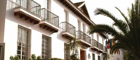 A two-story building with balconies, a flat roof, and a white facade.
