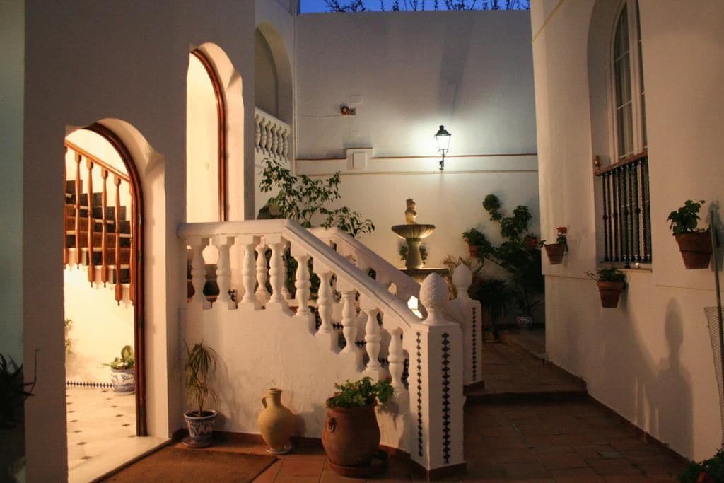 A staircase with white balustrades, a wall-mounted light fixture, and potted plants.