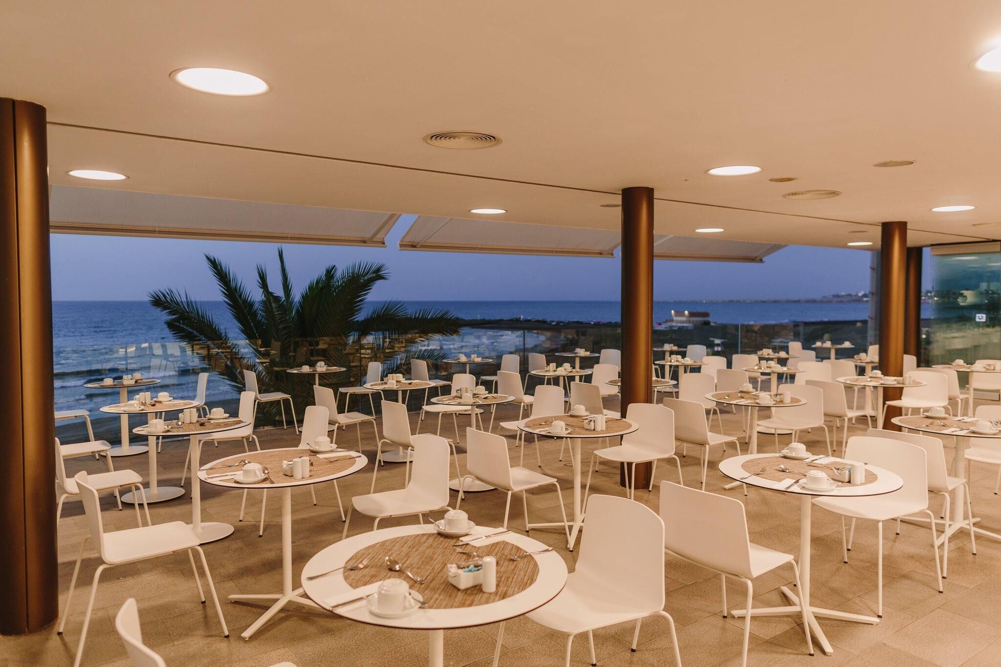 Un área de comedor en la azotea con mesas y sillas, con vistas al mar.