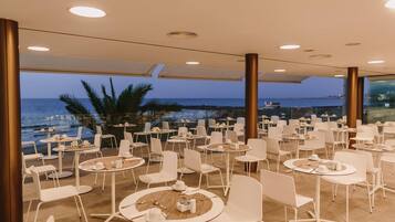 Un área de comedor en la azotea con mesas y sillas, con vistas al mar.