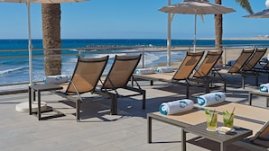 A beachside lounge area with sun loungers, umbrellas, and a view of the ocean. - Don Gregory by Dunas, Adults Only (San Bartolomé de Tirajana)