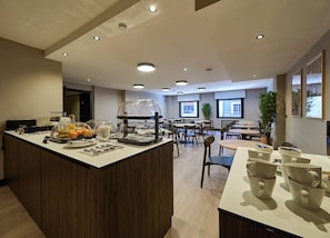 Un comedor moderno de hotel con una isla central, varias mesas y sillas.