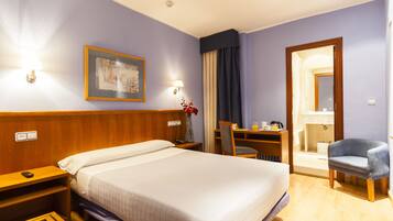 Minibar, escritorio, tabla de planchar con plancha y ropa de cama