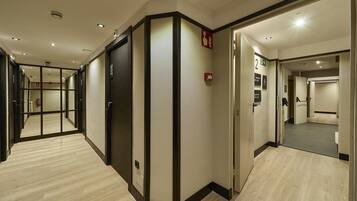 Un pasillo de hotel con un muro espejado, un detector de incendios y una puerta marcada con el número 2.