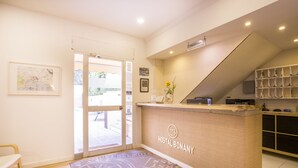 Una recepción con un letrero que dice "HOSTAL BONANY", un mapa en la pared y una escalera que lleva a un área de almacenamiento.
