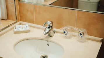 A bathroom sink with a mirror above it, a faucet, and two glass containers with blue text.