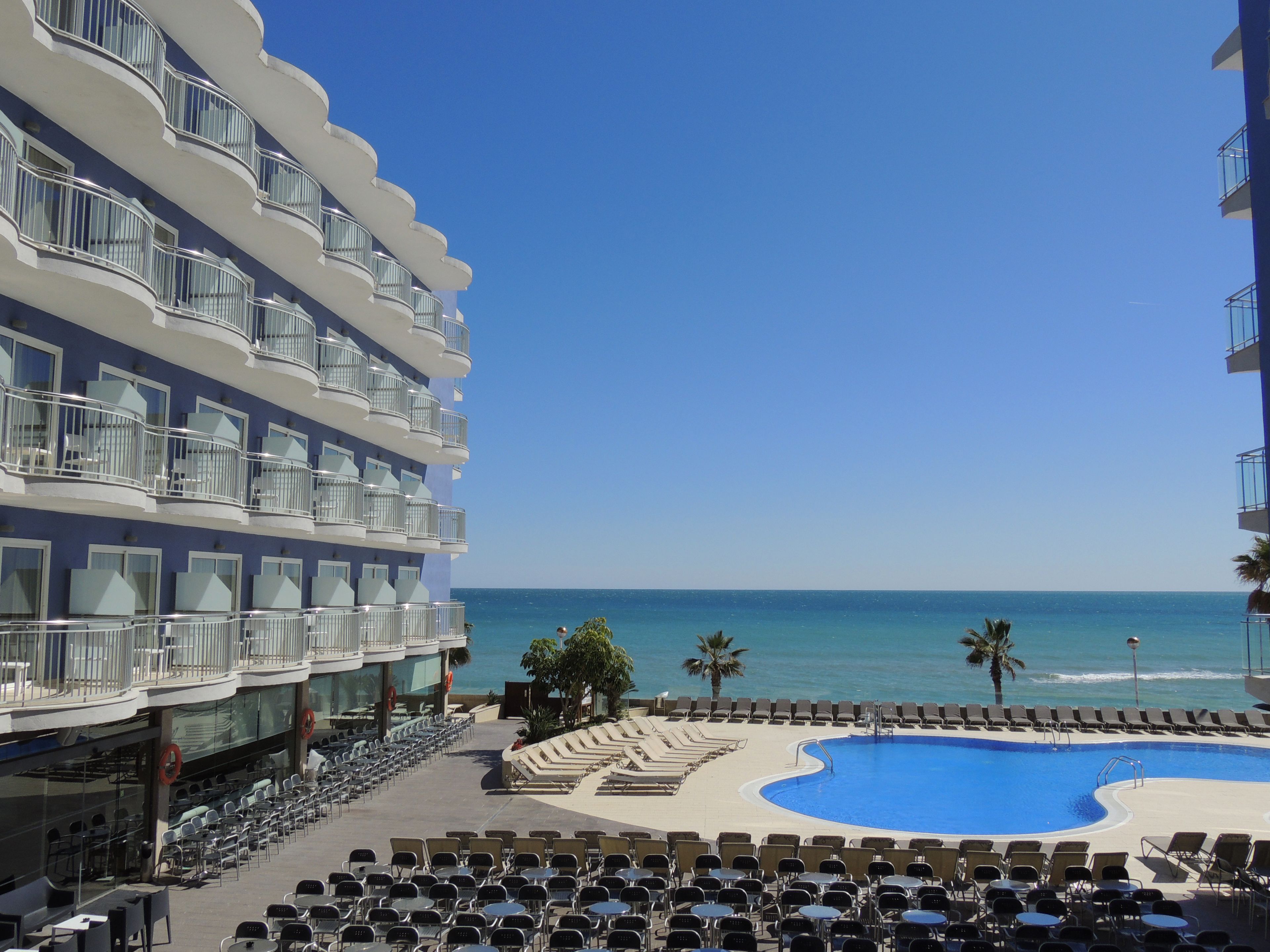 Un hotel con piscina, sillones de descanso y vista al océano.