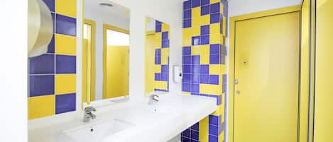 Un baño con dos lavabos, un espejo y una puerta amarilla.