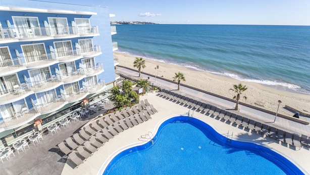 Un hotel con piscina, vista al mar y varios balcones.