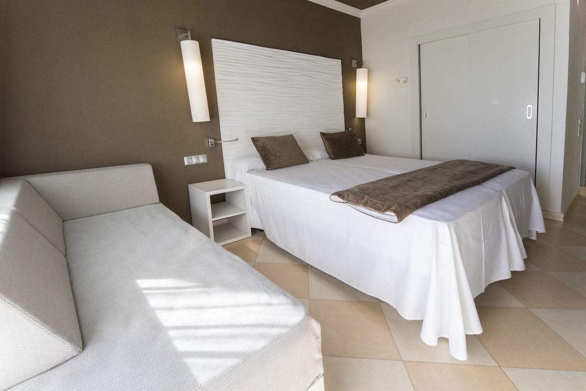 Une chambre d’hôtel moderne avec un grand lit, un canapé et une armoire.