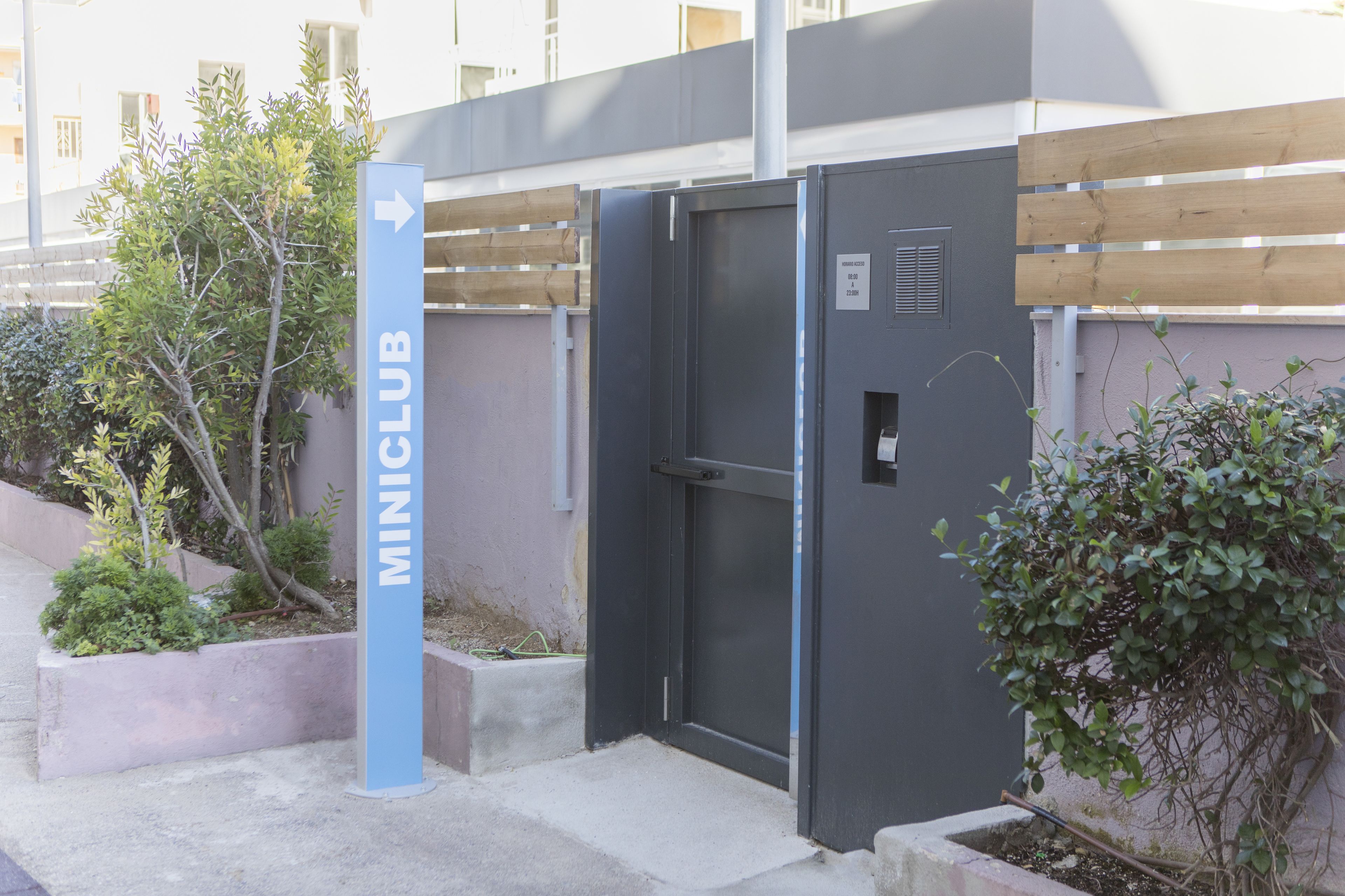 Une entrée d'immeuble avec une enseigne bleue portant l'inscription « MINICLUB » et une porte.