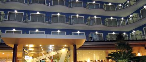 A multi-level hotel atrium with a central staircase, glass railings, and a sign reading "AUGUSTUS".