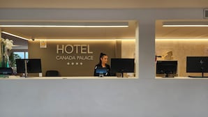 En hotellreception med en skylt som visar texten ”HOTEL CANADA PALACE” och en receptionist.