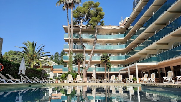 Ett hotell med pool, flera balkonger och utomhusområden med sittplatser.