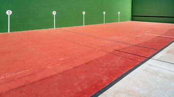 A tennis court with numbered service boxes and a green wall.