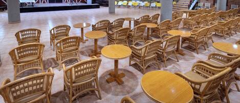 A spacious indoor area with multiple wicker tables and chairs arranged in rows.