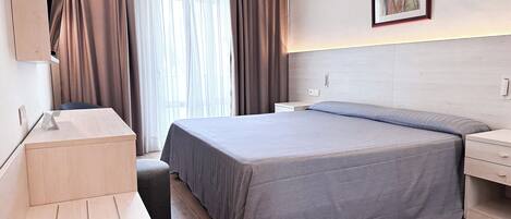 Una habitación de hotel moderna con una cama grande, un escritorio y una silla.