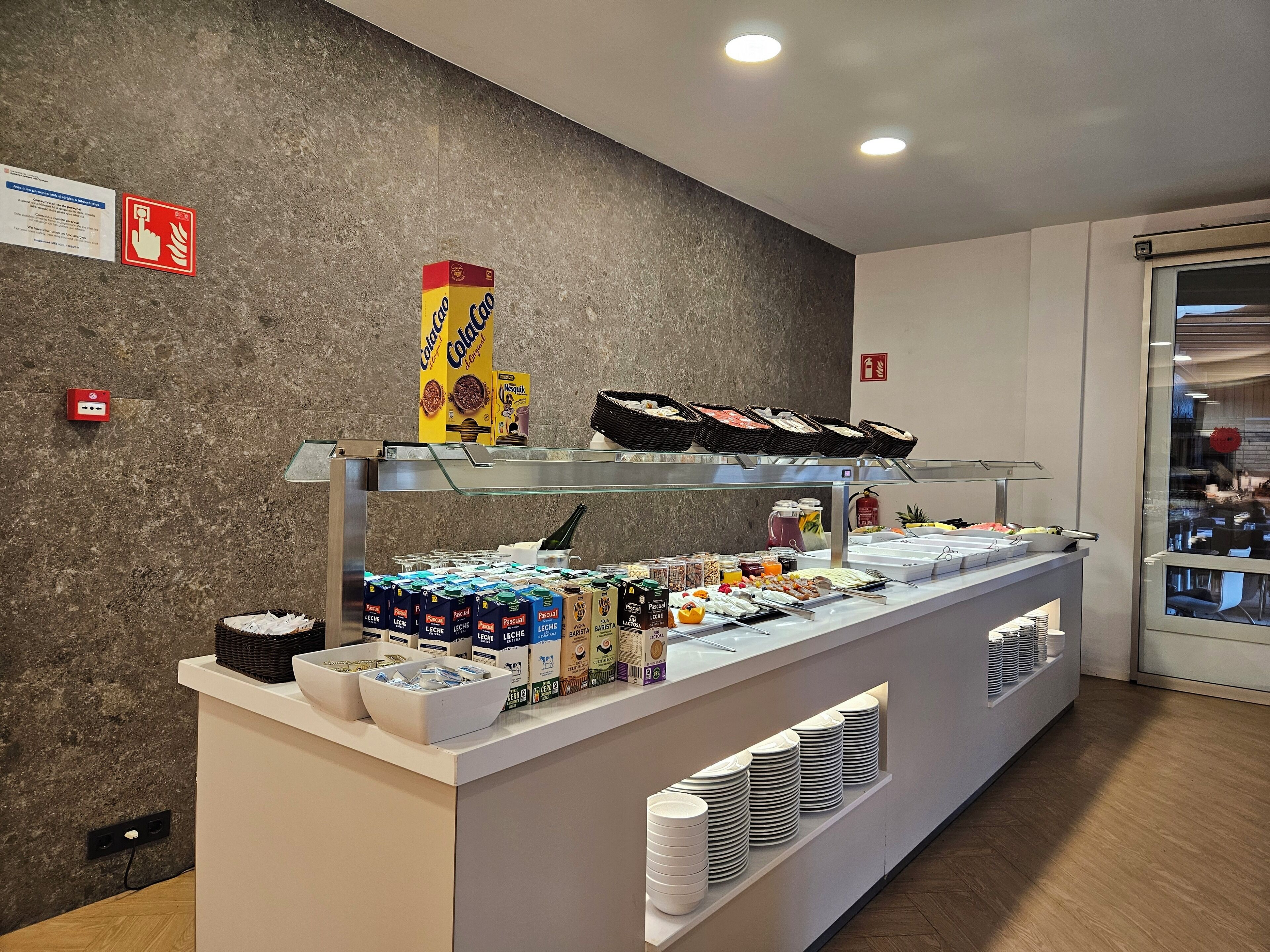 A breakfast bar with various food items and beverages, including cereal, milk, and juice.