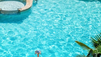 Una piscina techada, una piscina al aire libre, sombrillas
