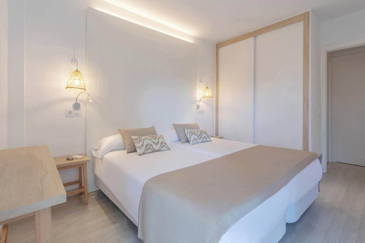 Un dormitorio con cama, mesitas de noche y lámparas de pared.