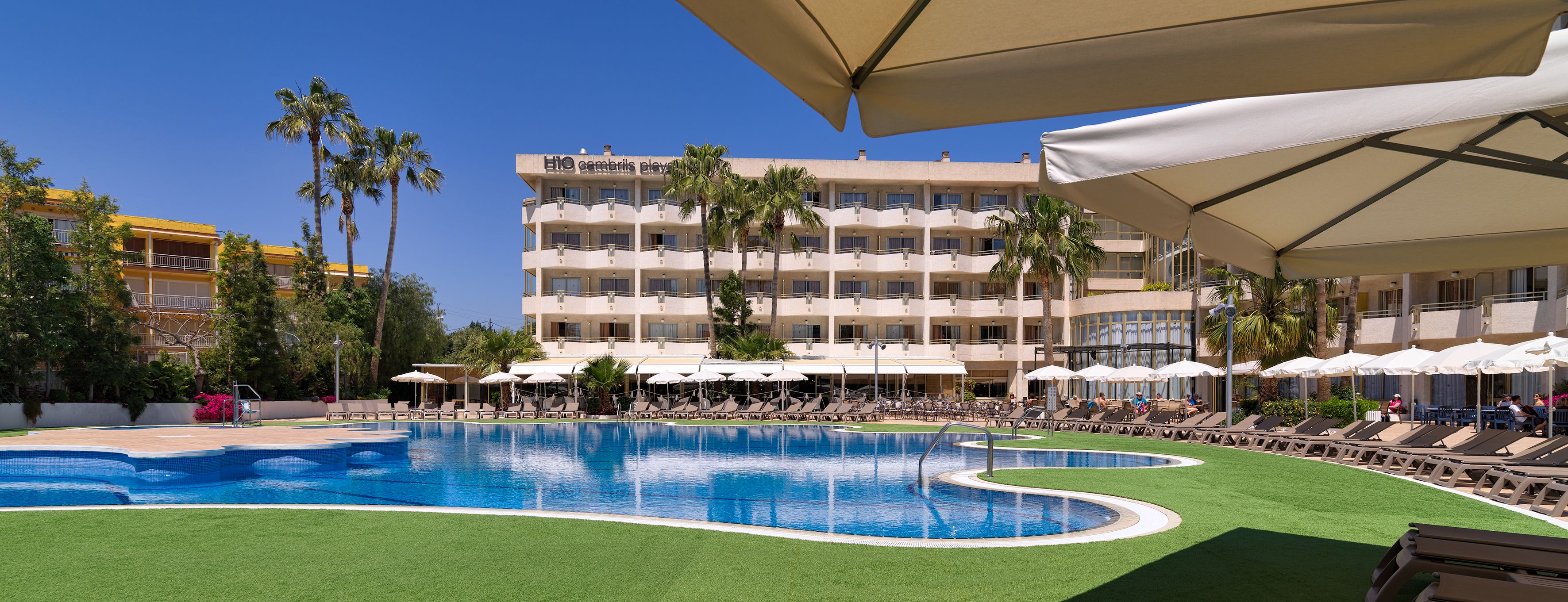 A hotel with a swimming pool, multiple balconies, and outdoor seating areas.