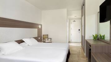 Ein Hotelzimmer mit einem großen Bett, einem Holzkopfschild, einem Nachttisch, einem Spiegel und einem Fernseher.