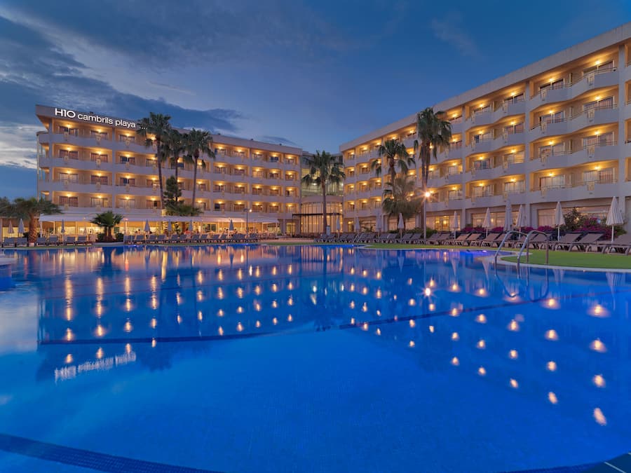 Un hotel con varios balcones, piscina y palmeras.