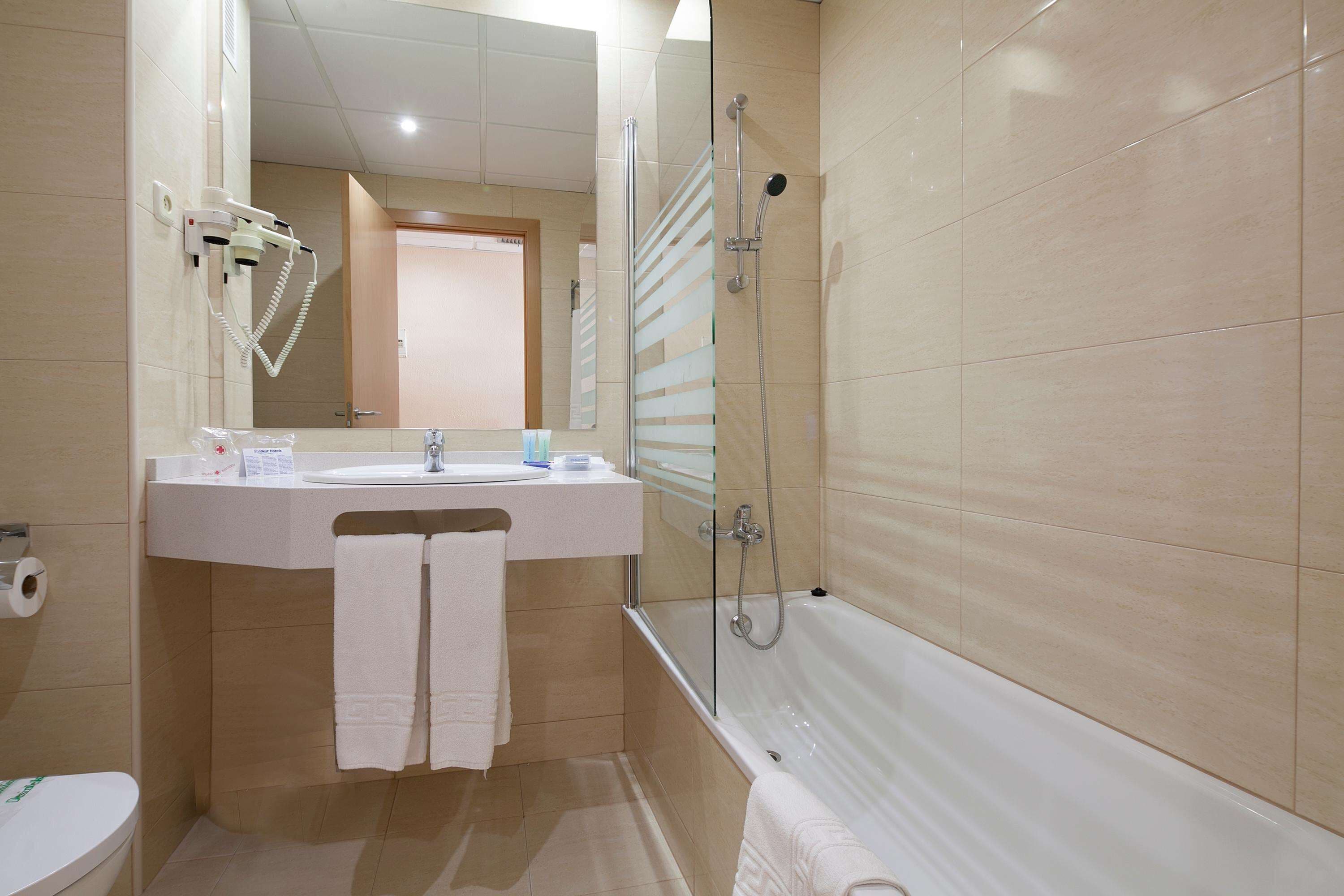 Un baño con bañera, lavamanos e inodoro.