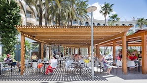 An outdoor patio area with wooden pergolas, white chairs, and tables. - Hotel Best Cambrils (Cambrils)