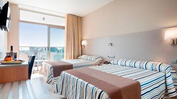 A hotel room with two beds, a desk with a chair, and a large window offering a city view.