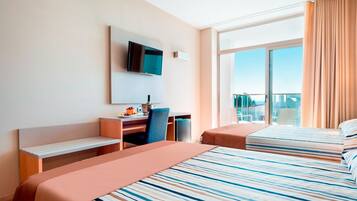 Habitación de hotel con cama, escritorio, silla, televisión y ventana con cortinas.
