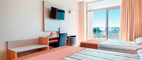 A hotel room with a bed, a desk, a chair, a television, and a window with curtains.