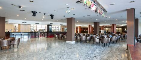 A spacious lobby with a marble floor, a bar area, and numerous seating arrangements.