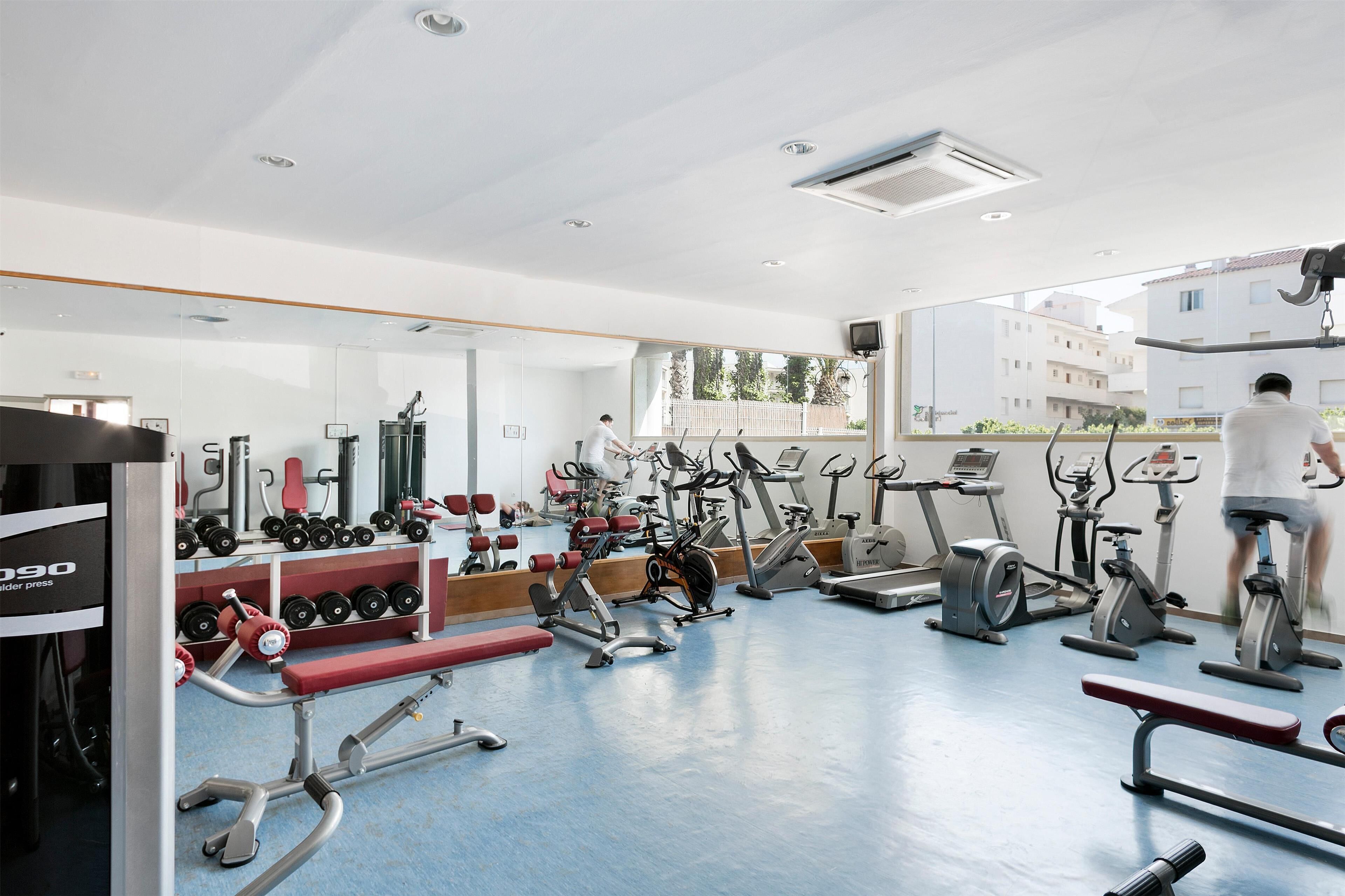 Un gimnasio con diversos equipos de ejercicio, incluyendo cintas de correr, bicicletas estáticas y máquinas de pesas.