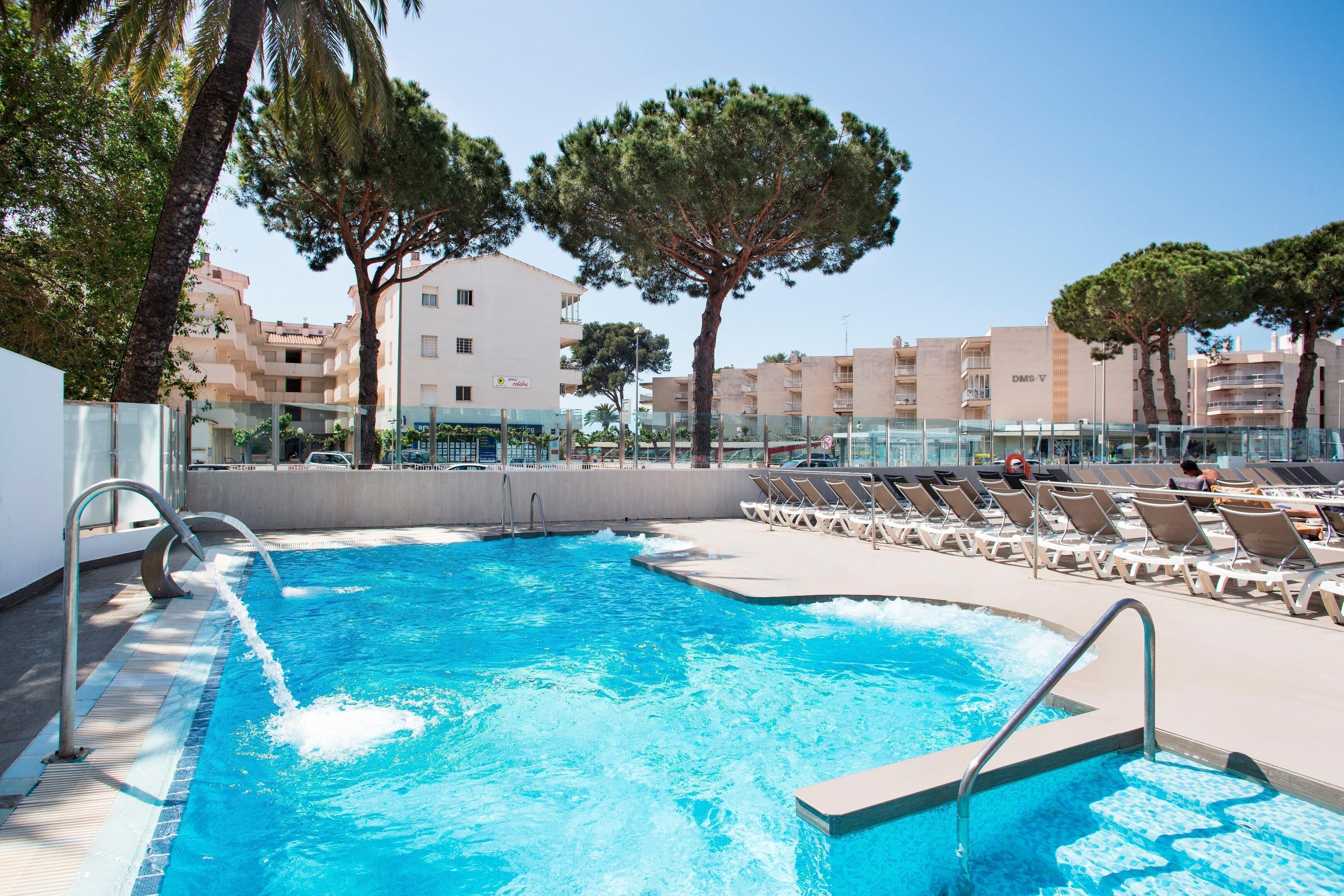 A swimming pool with lounge chairs and a clear view of the surrounding buildings.