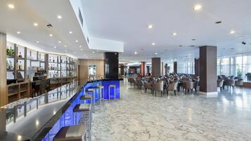 Un vestíbulo amplio con zona de bar, asientos y suelo de mármol.