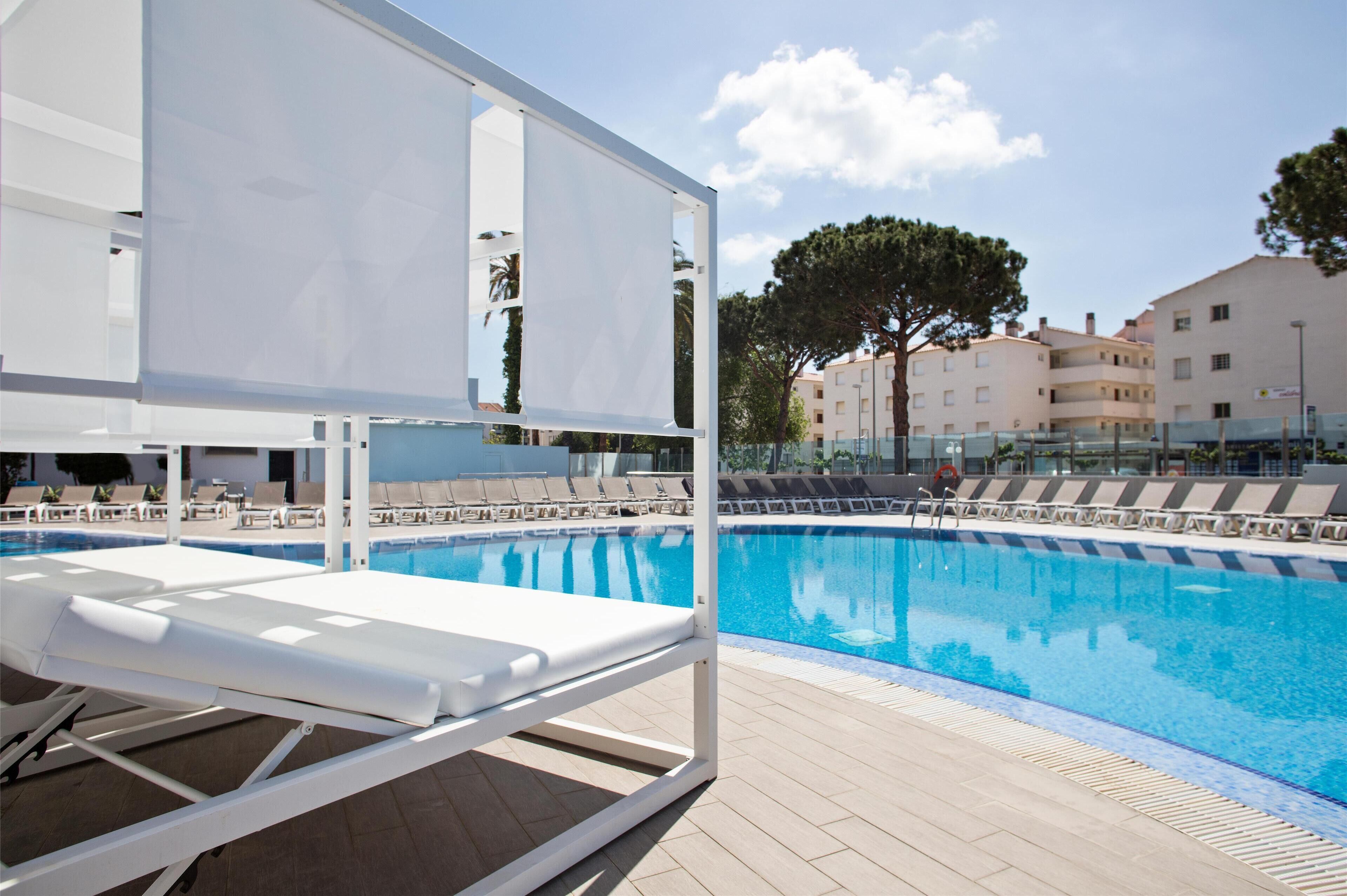 A poolside area with sun loungers and a clear blue pool.