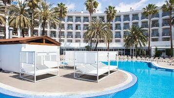 A hotel pool area with sun loungers and palm trees.