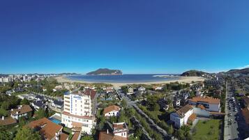 A hotel with multiple floors, a swimming pool, and a view of the beach and ocean.