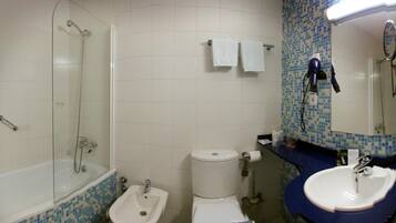 A bathroom with a glass-enclosed shower, a bidet, a toilet, a sink, and a mirror.