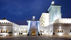 Gran y luminosa entrada de hotel con un llamativo letrero de 'ABADES HOTELS', que presenta un estilo arquitectónico tradicional con arcos y tejado de tejas.